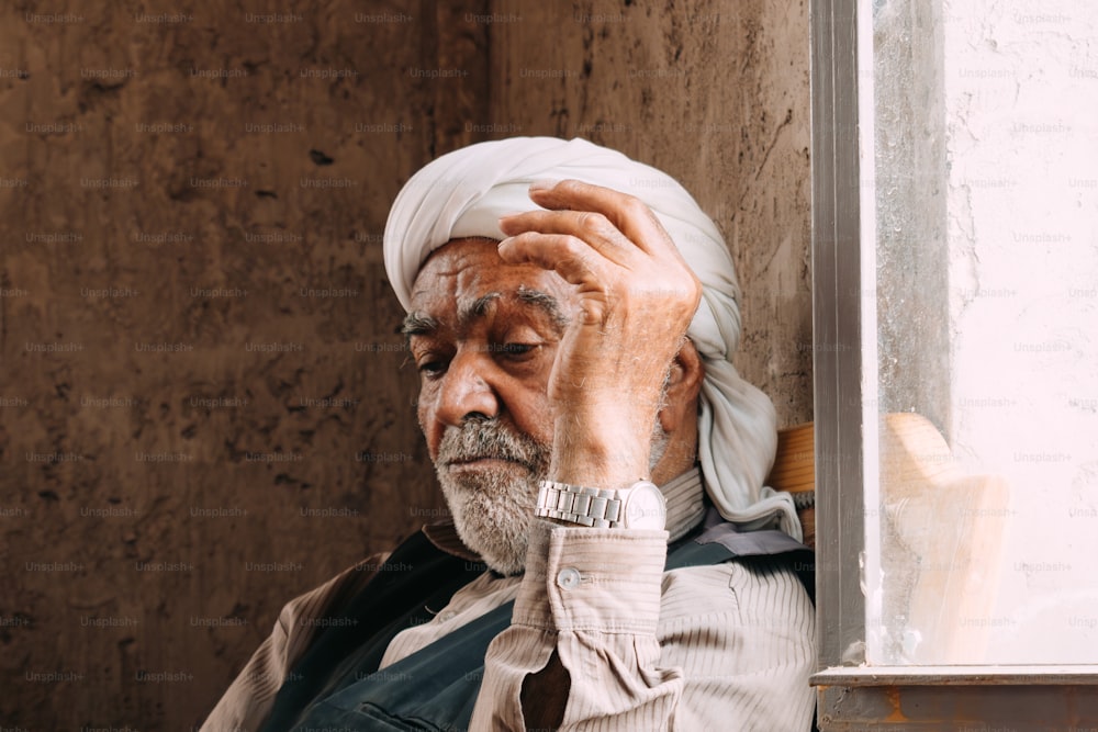 Ein Mann mit weißem Turban lehnt an einer Wand
