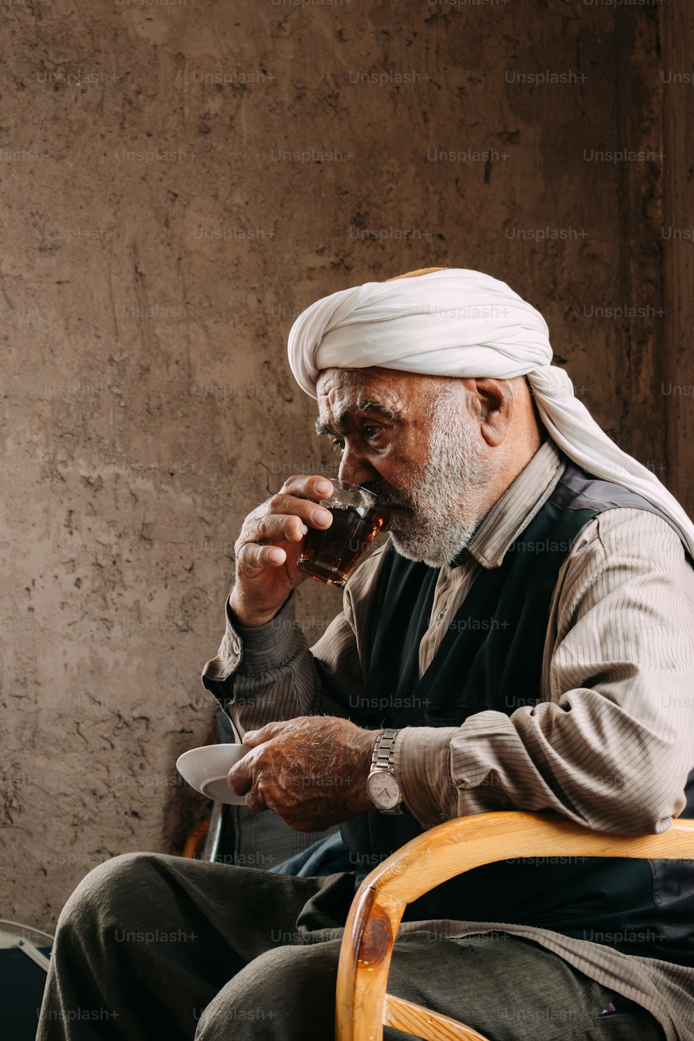 a man sitting in a chair drinking from a glass