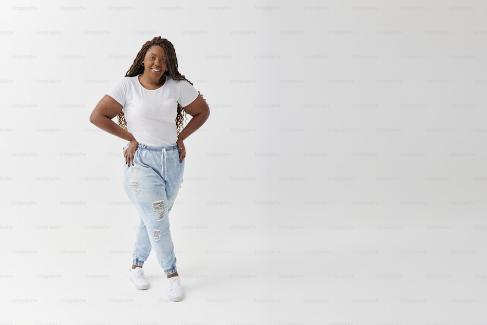 Une femme en chemise blanche et jeans posant pour une photo