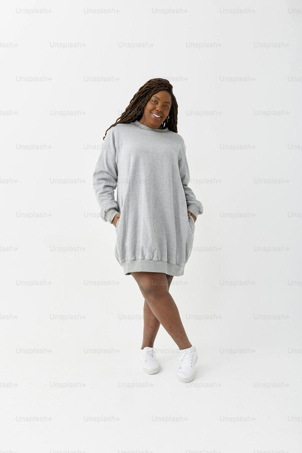 a woman wearing a grey sweater dress and white tennis shoes