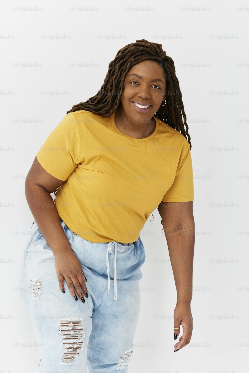 Una mujer con camisa amarilla y jeans rotos