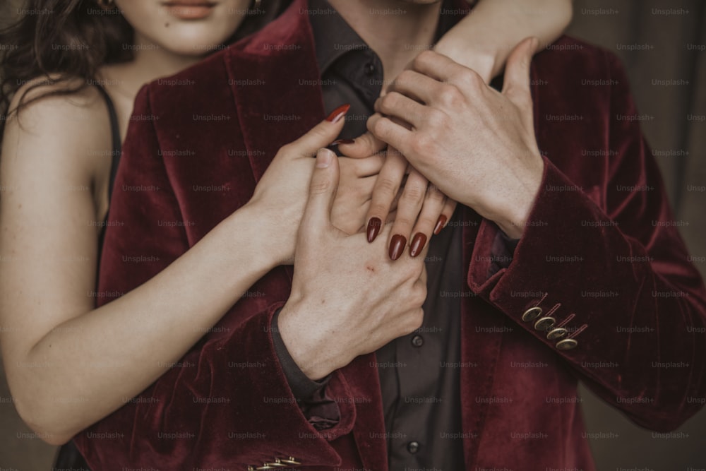 a man in a red velvet jacket holding a woman's hand