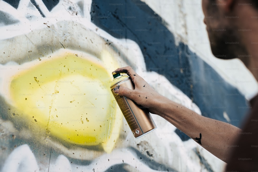 a man spray painting a wall with yellow paint