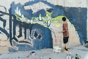 um homem pintando um mural na lateral de um prédio