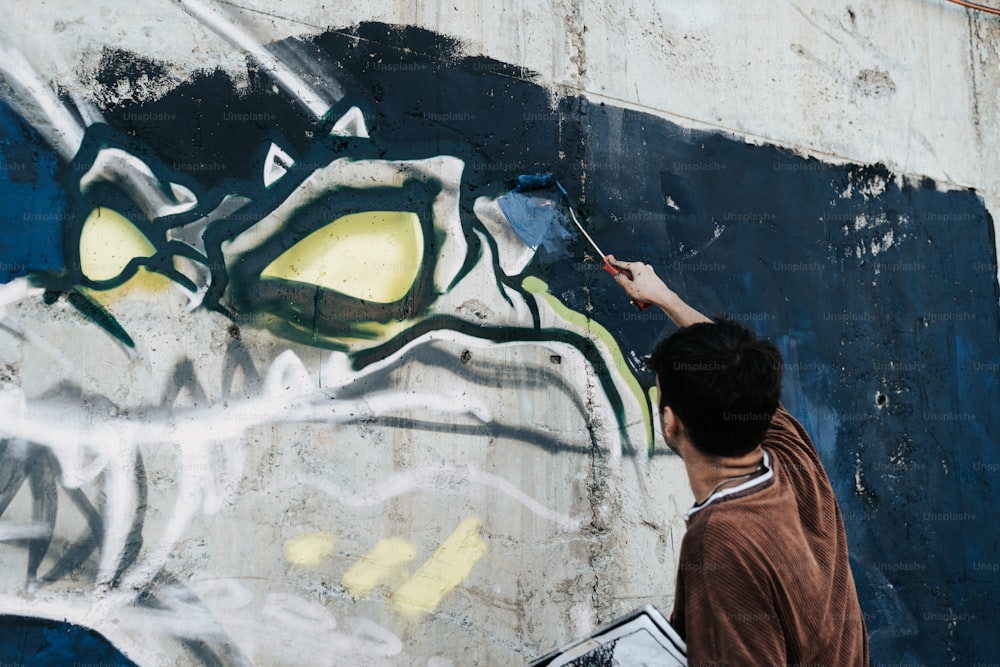 um homem pintando grafite em uma parede com um pincel