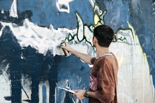 a man is painting a wall with graffiti