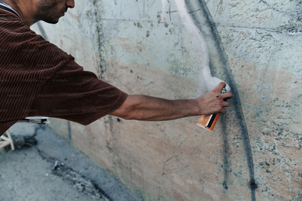 a man spray painting a wall with a paint roller