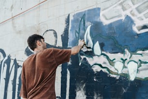 Un homme peignant un mur avec de la peinture bleue et blanche
