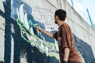 a man painting a wall with graffiti on it