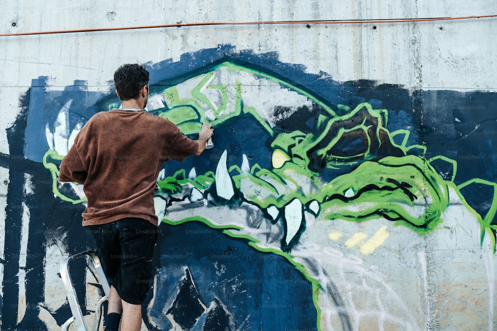 Ein Mann malt ein Wandbild an eine Wand