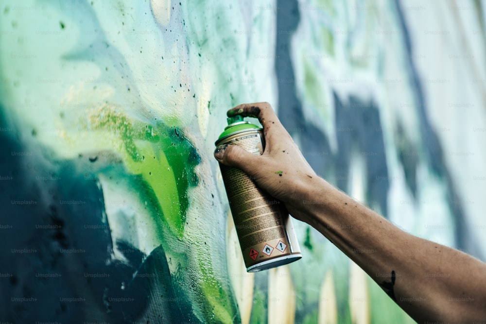 a person spray painting a wall with green paint