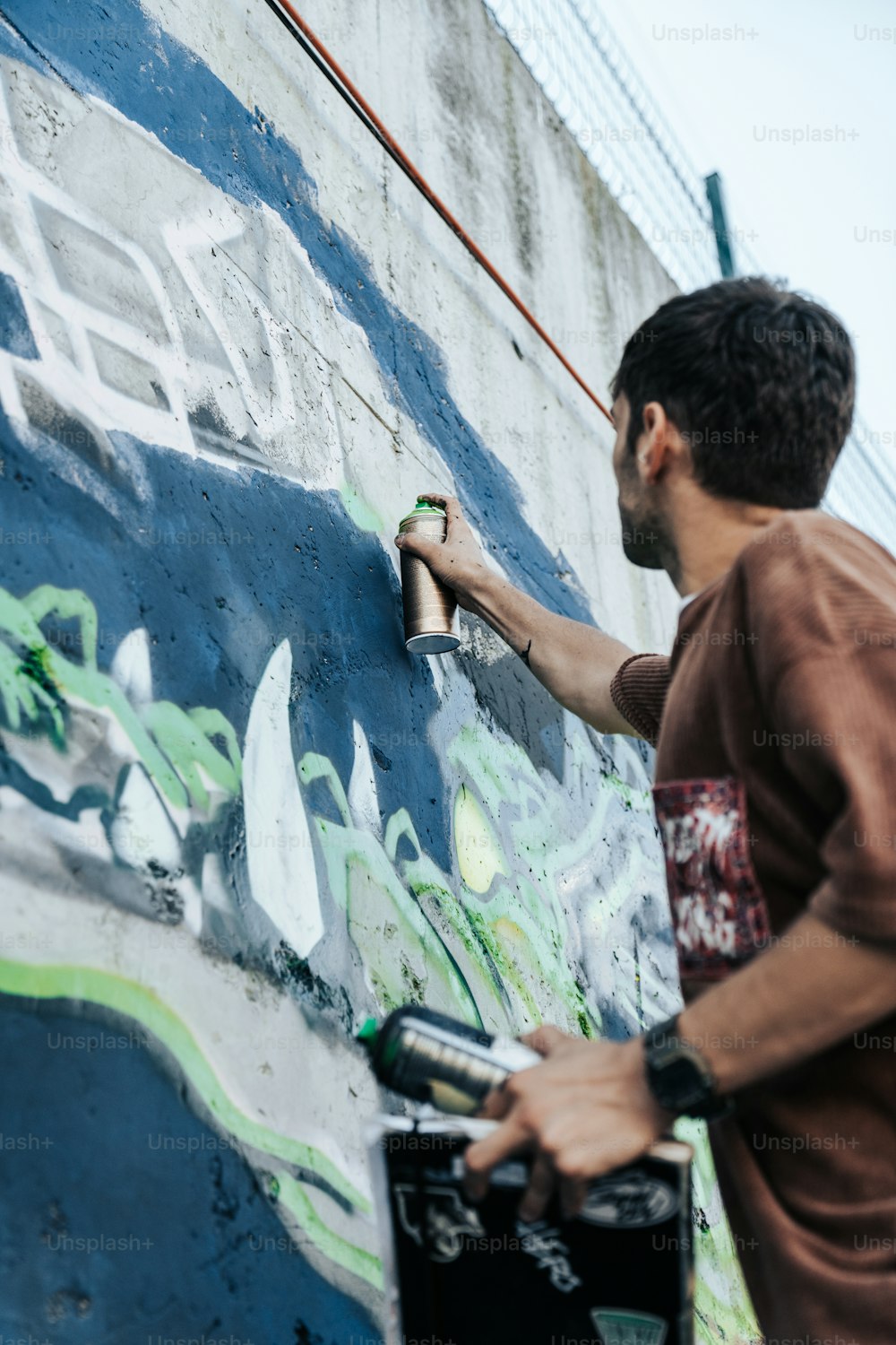 a man painting a wall with graffiti on it