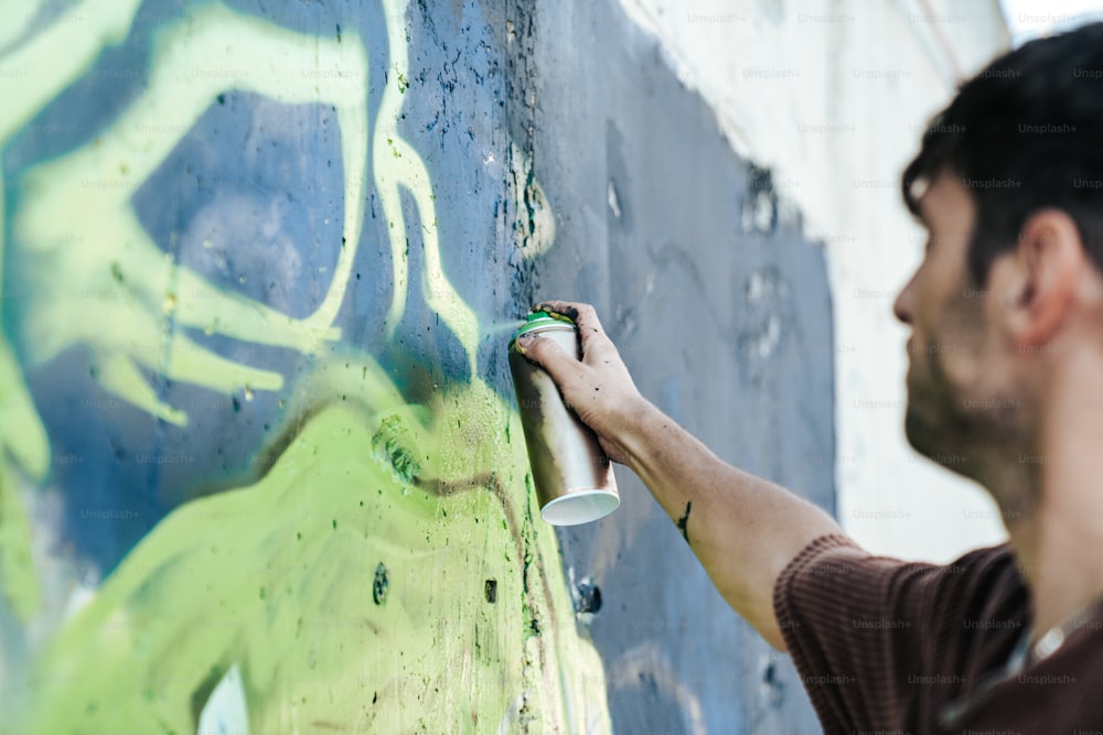 a man painting a wall with green and blue spray paint