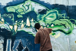 a man standing in front of a wall covered in graffiti