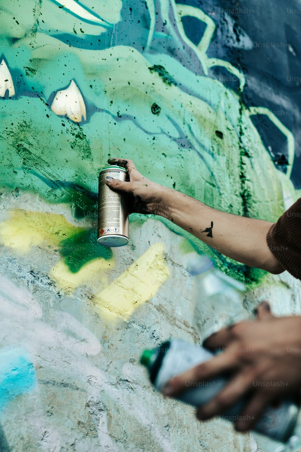 a person spray painting a wall with green and blue colors