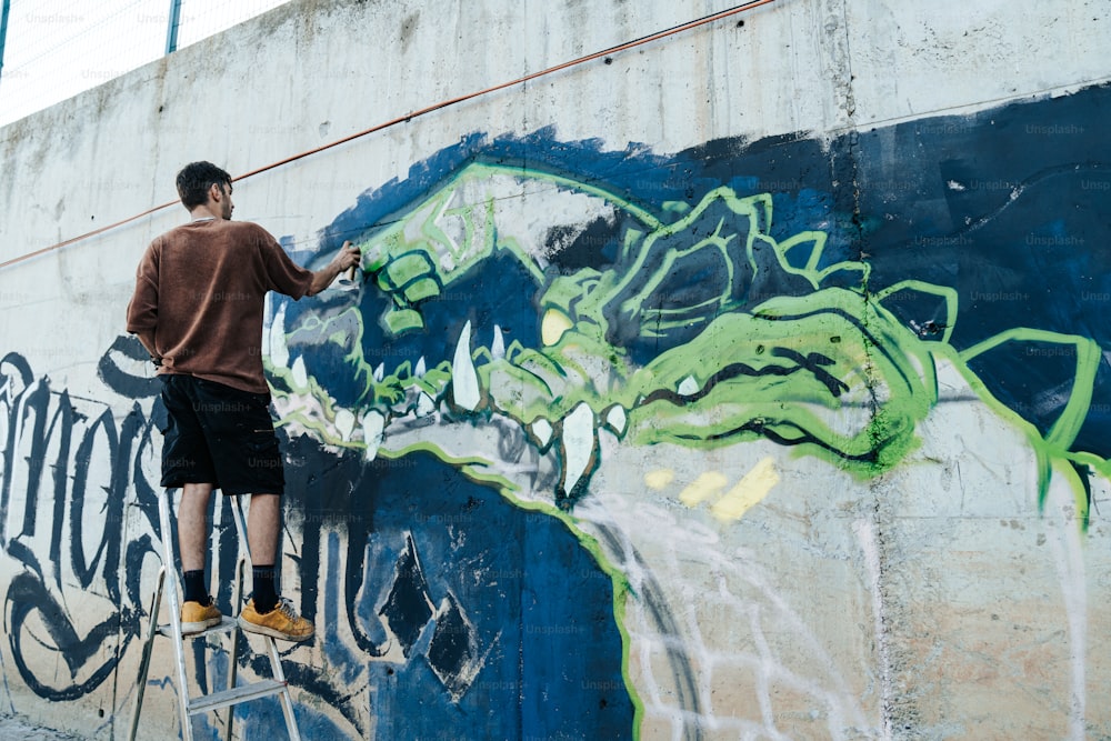 Un homme peignant un mur avec des graffitis dessus