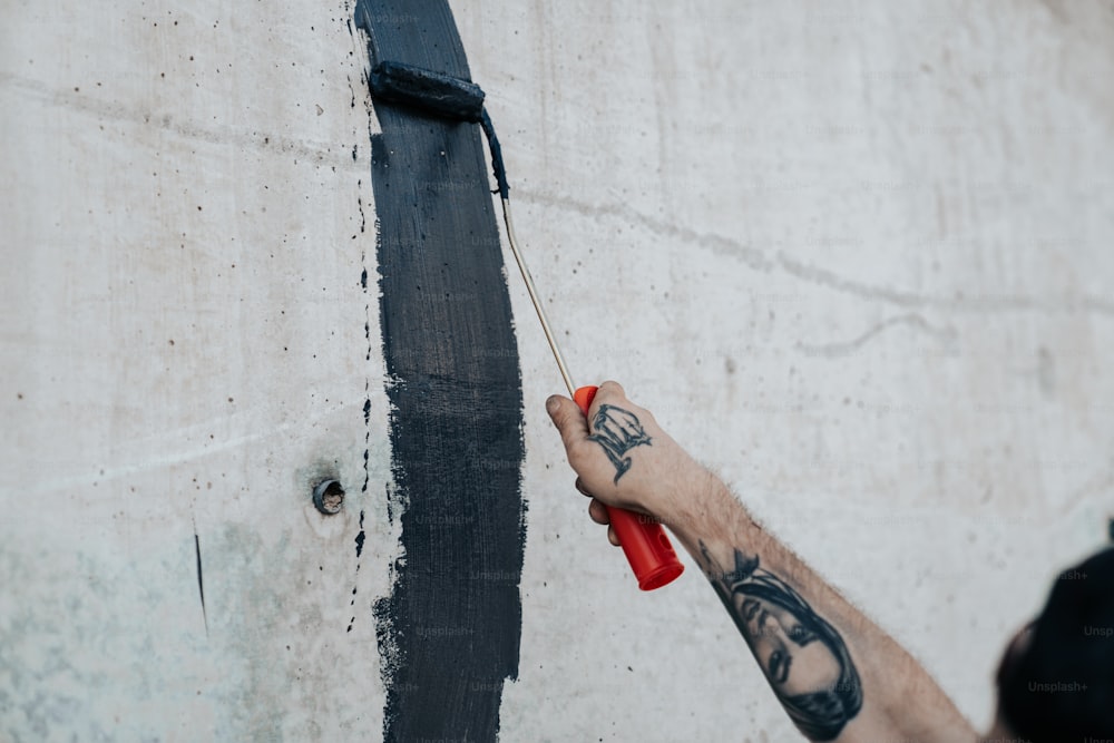 a man is painting a wall with black paint
