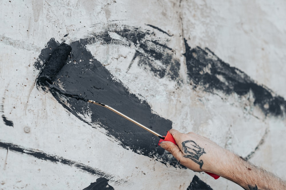 Un hombre está pintando una pared con pintura negra