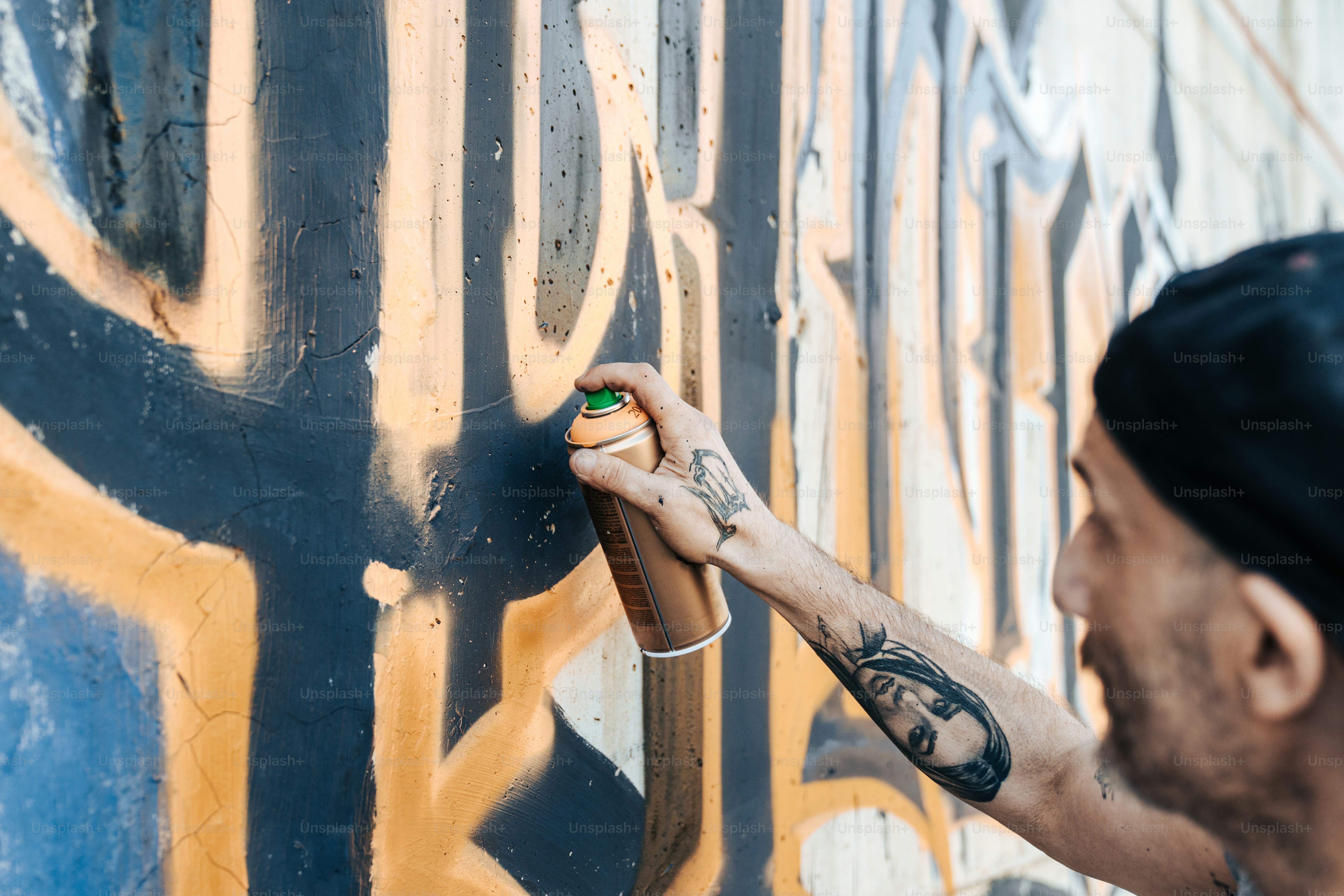 Un hombre parado frente a una pared cubierta de graffiti foto – Imagen ...