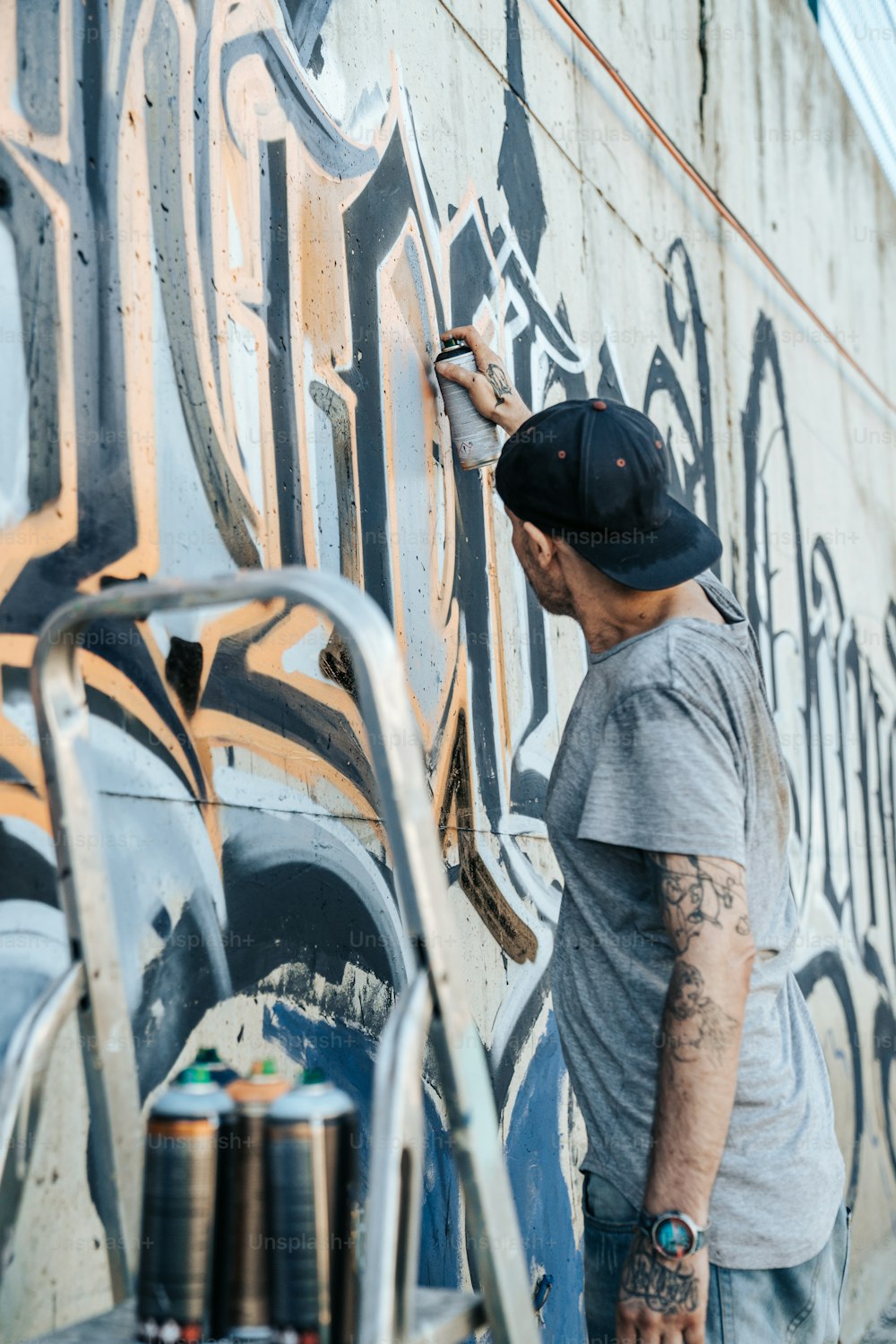 Un homme peignant un mur avec des graffitis dessus