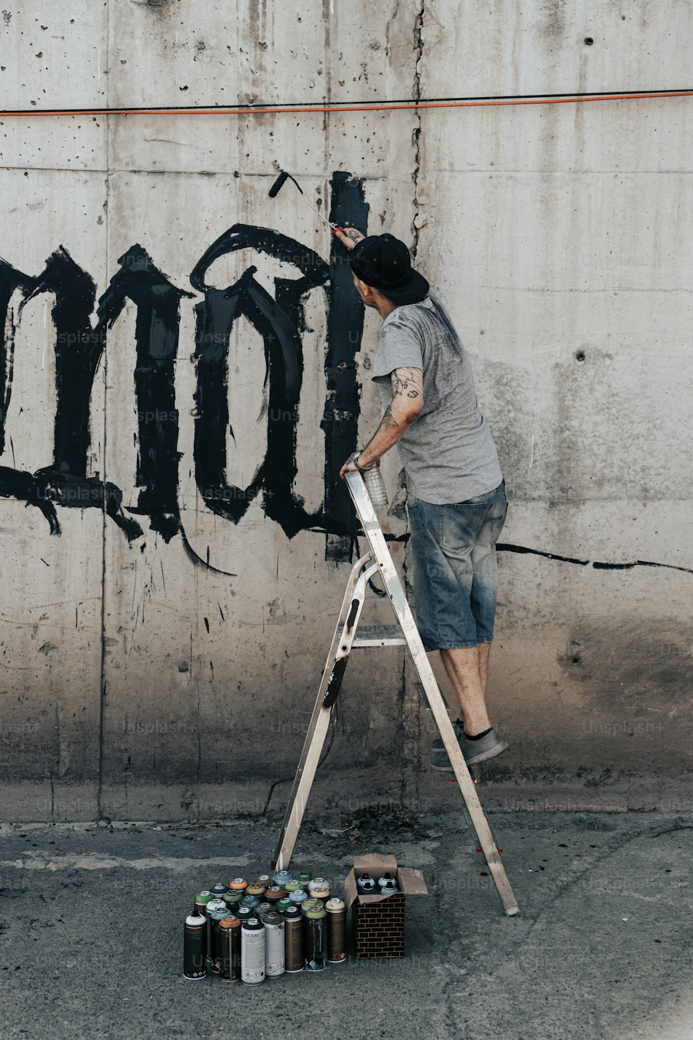 a man on a ladder painting graffiti on a wall