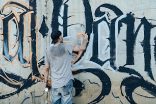 a man is painting a wall with graffiti