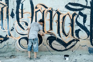 Un uomo in piedi di fronte a un muro coperto di graffiti
