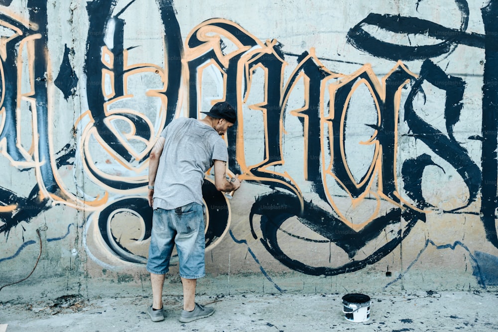 Un hombre parado frente a una pared cubierta de graffiti