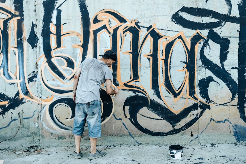 a man standing in front of a graffiti covered wall