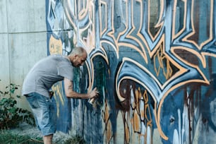 Um homem está pintando um muro com pichações