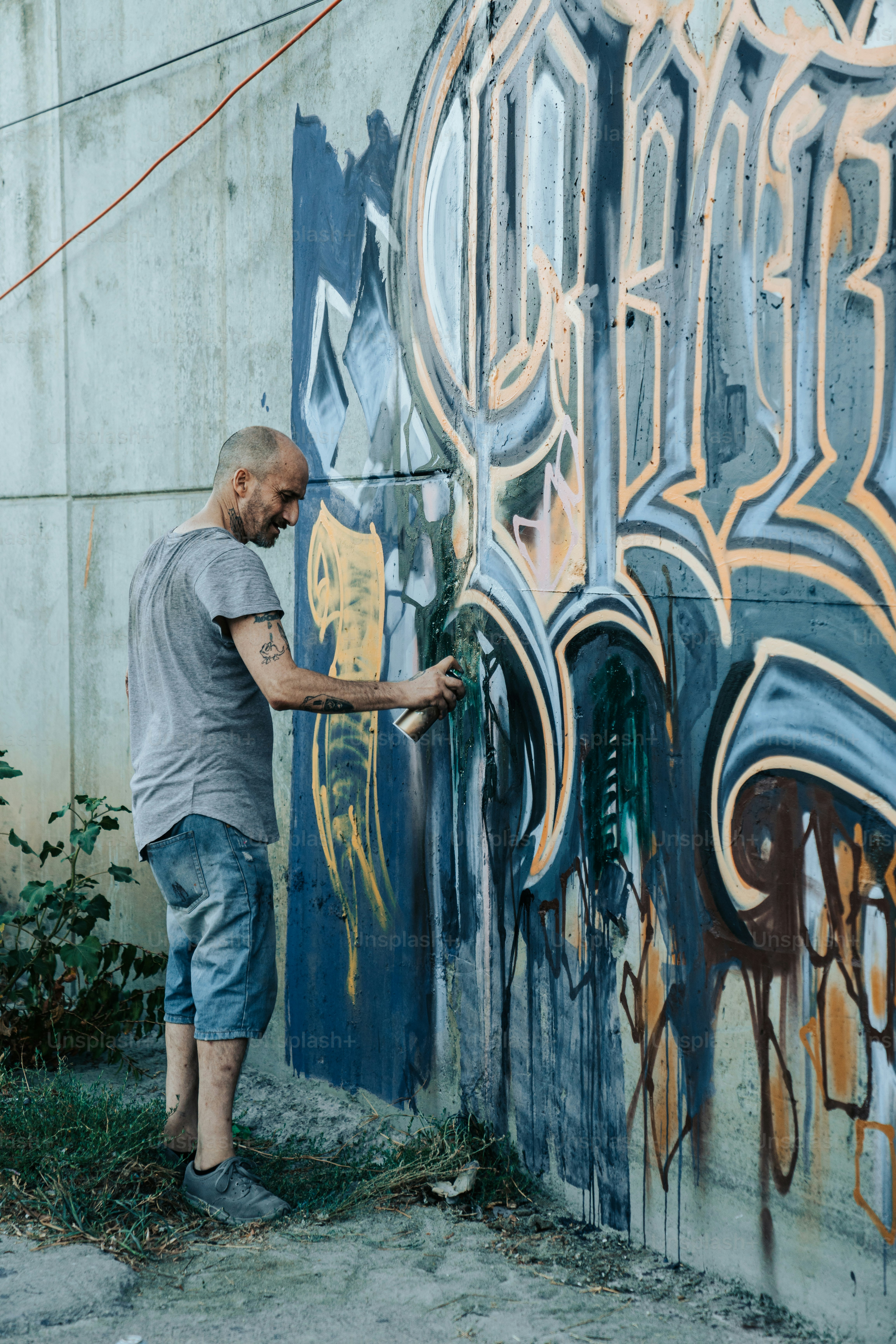 Un hombre parado frente a una pared cubierta de graffiti foto – Imagen ...