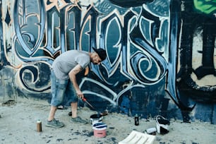Um homem está pintando grafite em uma parede