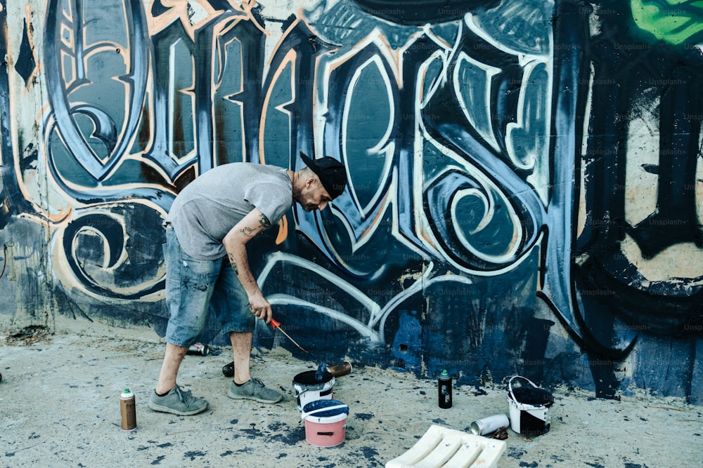Un hombre está pintando graffiti en una pared