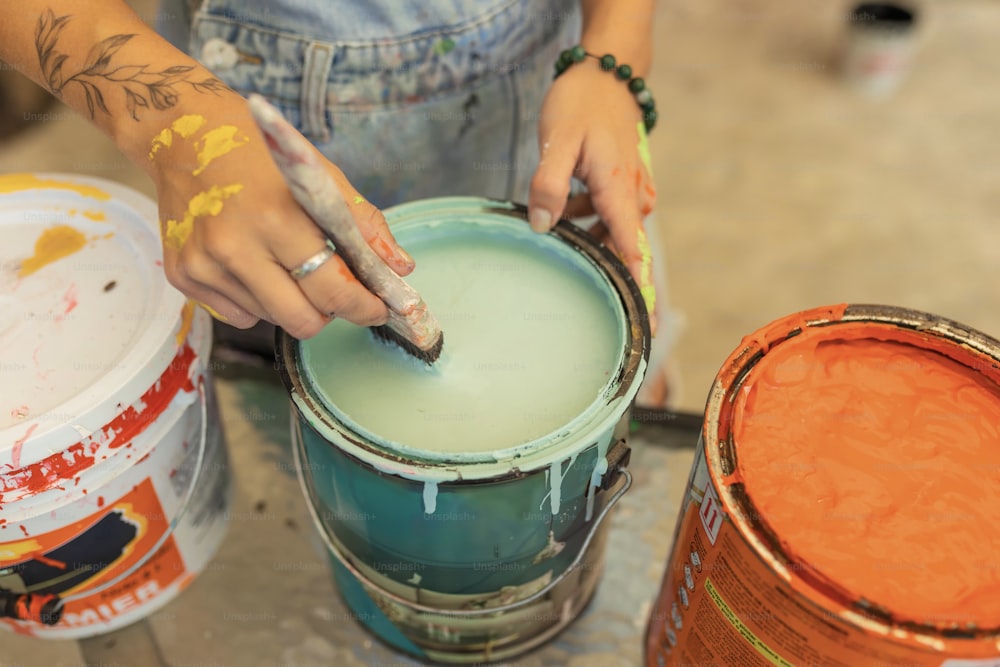 a person is painting a bucket with orange paint