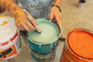 Una persona sta dipingendo un secchio con vernice arancione