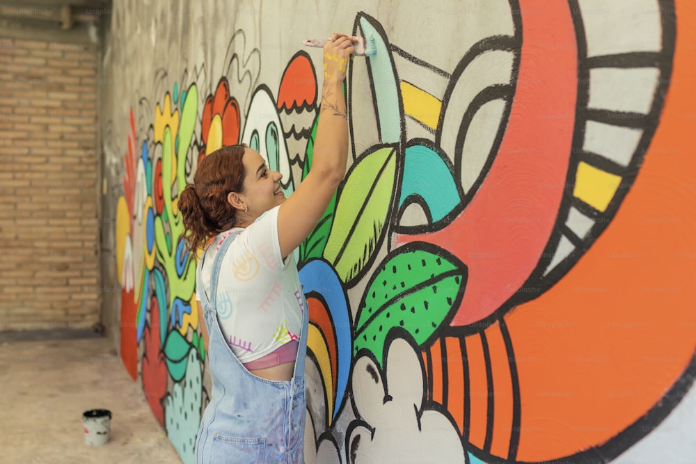 a woman painting a mural on a wall