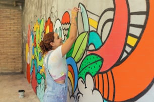 a woman painting a mural on a wall