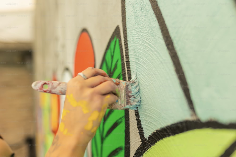 uma mulher pintando uma parede com um pincel