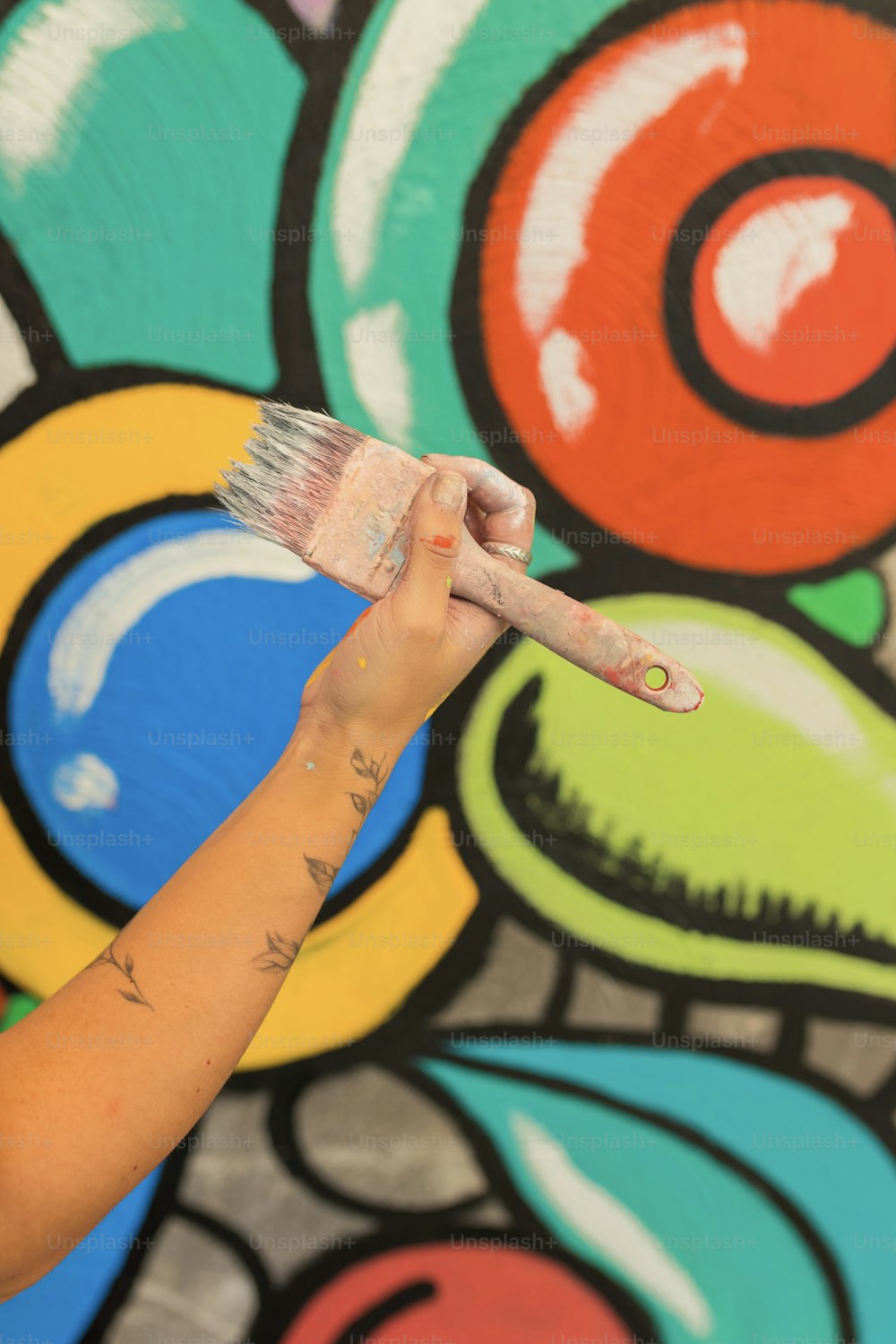 a person holding a paintbrush in front of a colorful wall