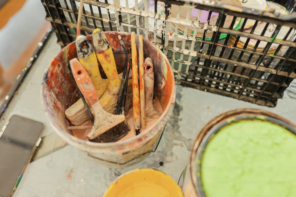a bucket filled with paint next to a yellow bucket
