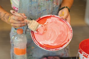 한 여자가 붓으로 빨간 그릇을 칠하고 있다