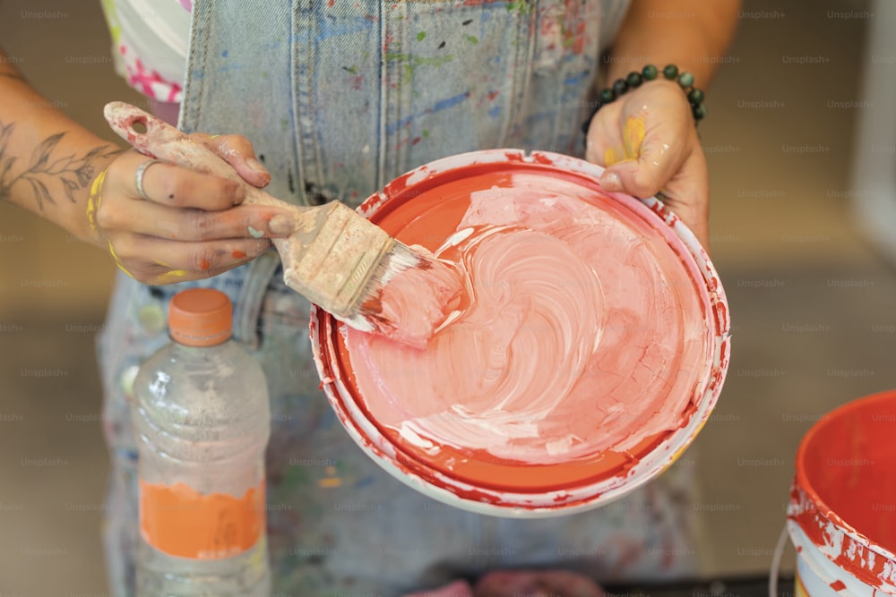 a woman is painting a red bowl with a brush