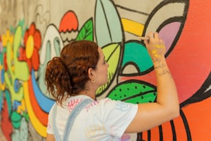 uma mulher pintando uma parede com grafite colorido