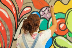 Una donna sta dipingendo un muro con graffiti colorati