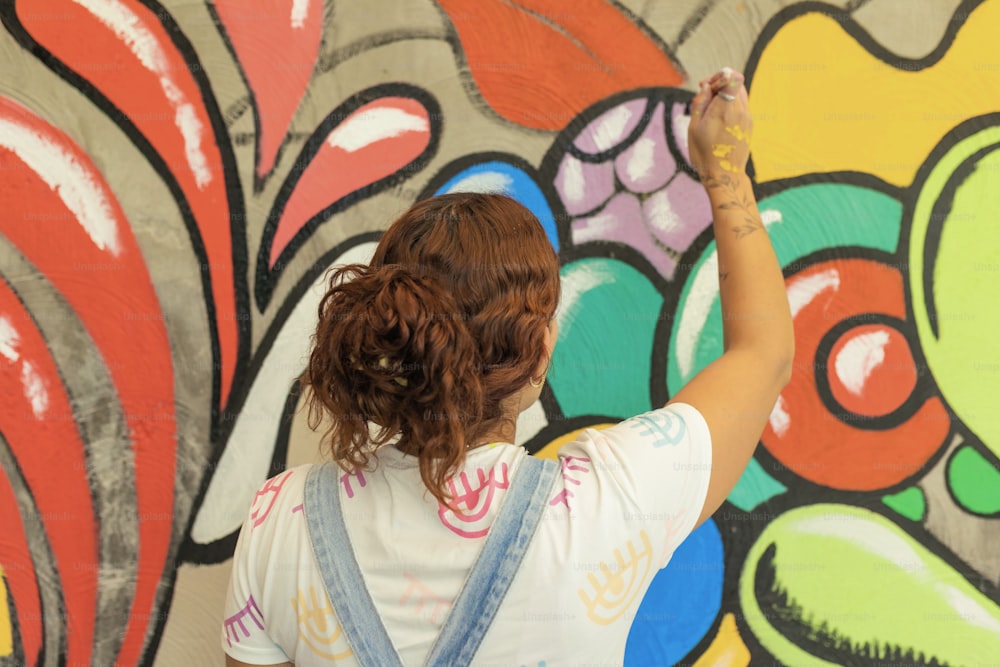 a woman is painting a wall with colorful graffiti