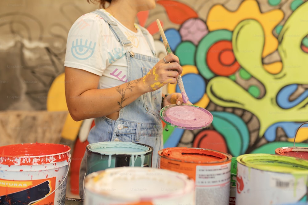 uma mulher de macacão pintando um mural em uma parede
