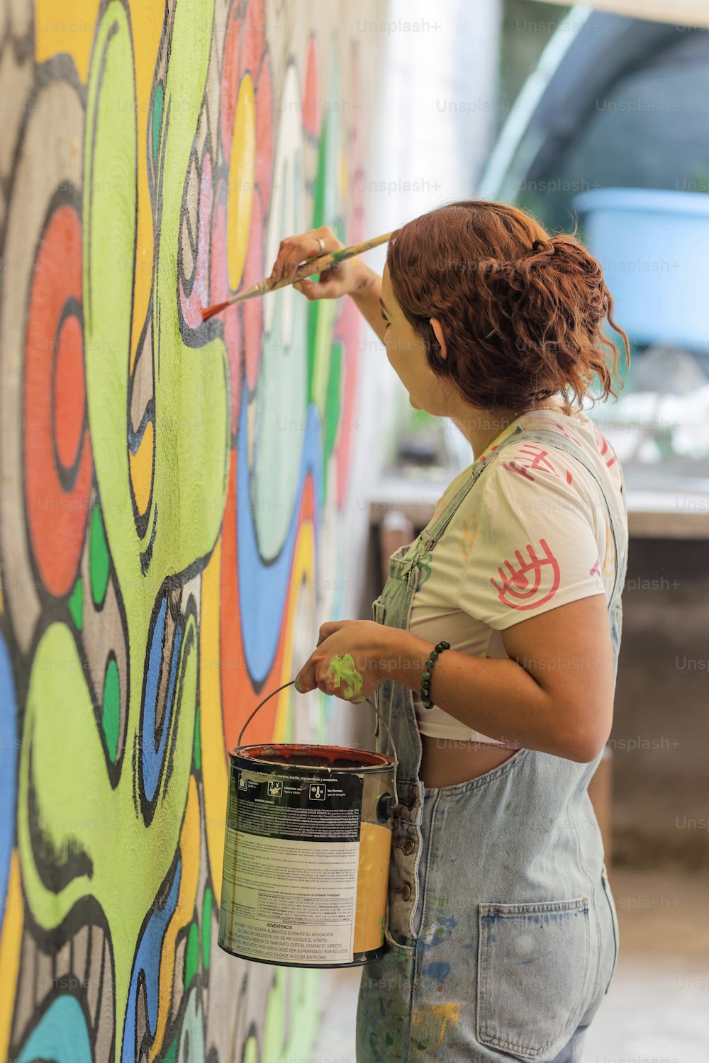 a woman painting a wall with a paintbrush