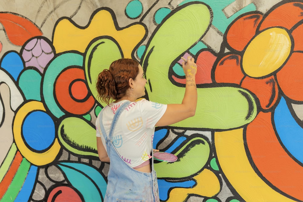 a woman is painting a mural on a wall