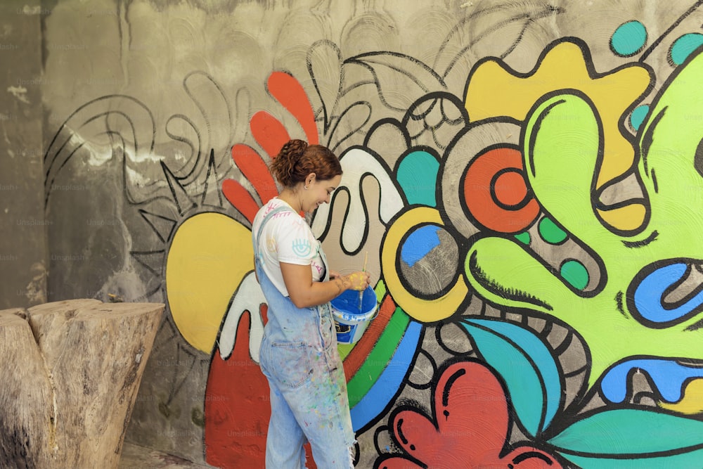 a woman is painting a mural on a wall