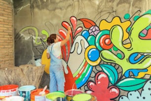 a woman painting a mural on the side of a building